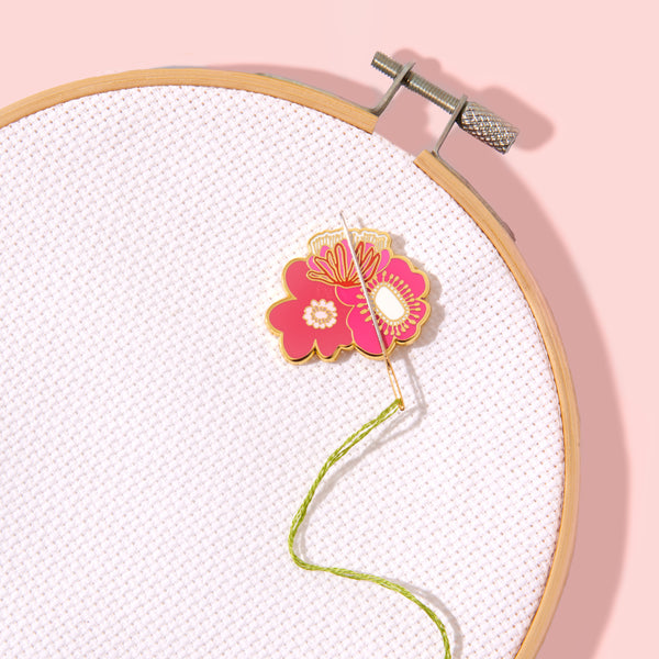 Embroidery hoop with pink floral design on white fabric against a pink background