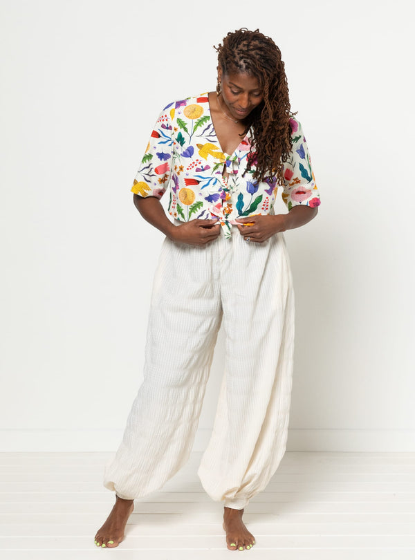 Person wearing a colorful floral shirt and white pants made using Sophia Woven Bubble Skirt and Pant sewing pattern on a white background