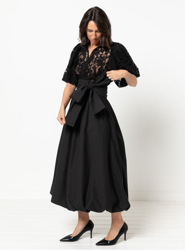 Woman wearing a black skirt made using Sophia Woven Bubble Skirt and Pant sewing pattern with lace detailing on a white background