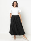 Woman wearing a white t-shirt and black skirt made using Sophia Woven Bubble Skirt and Pant sewing pattern on a white background