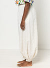 Person wearing white dhoti pants made using Sophia Woven Bubble Skirt and Pant sewing pattern with a plain background