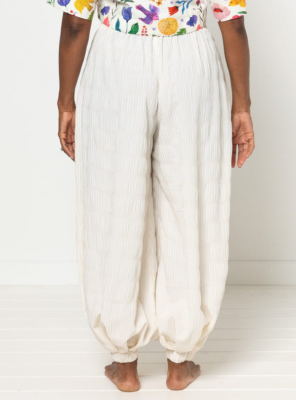 Person wearing white harem pants made using Sophia Woven Bubble Skirt and Pant sewing pattern and a colorful top on a white background