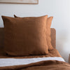 Tobacco brown European linen pillowcases on a bed with a neutral background