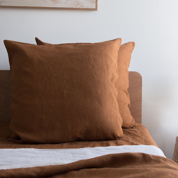 Tobacco brown European linen pillowcases on a bed with a neutral background